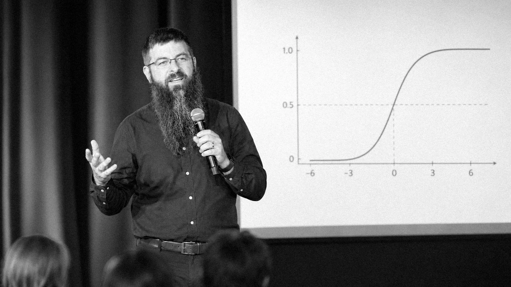Justin McCarthy speaking on stage in front of an adoption-curve chart
